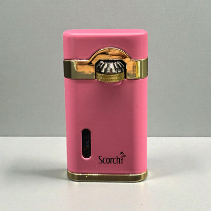 A pink Scorch electronic cigarette lighter with gold trim and a metallic ignition button, standing upright on a light gray surface against a gray background.
