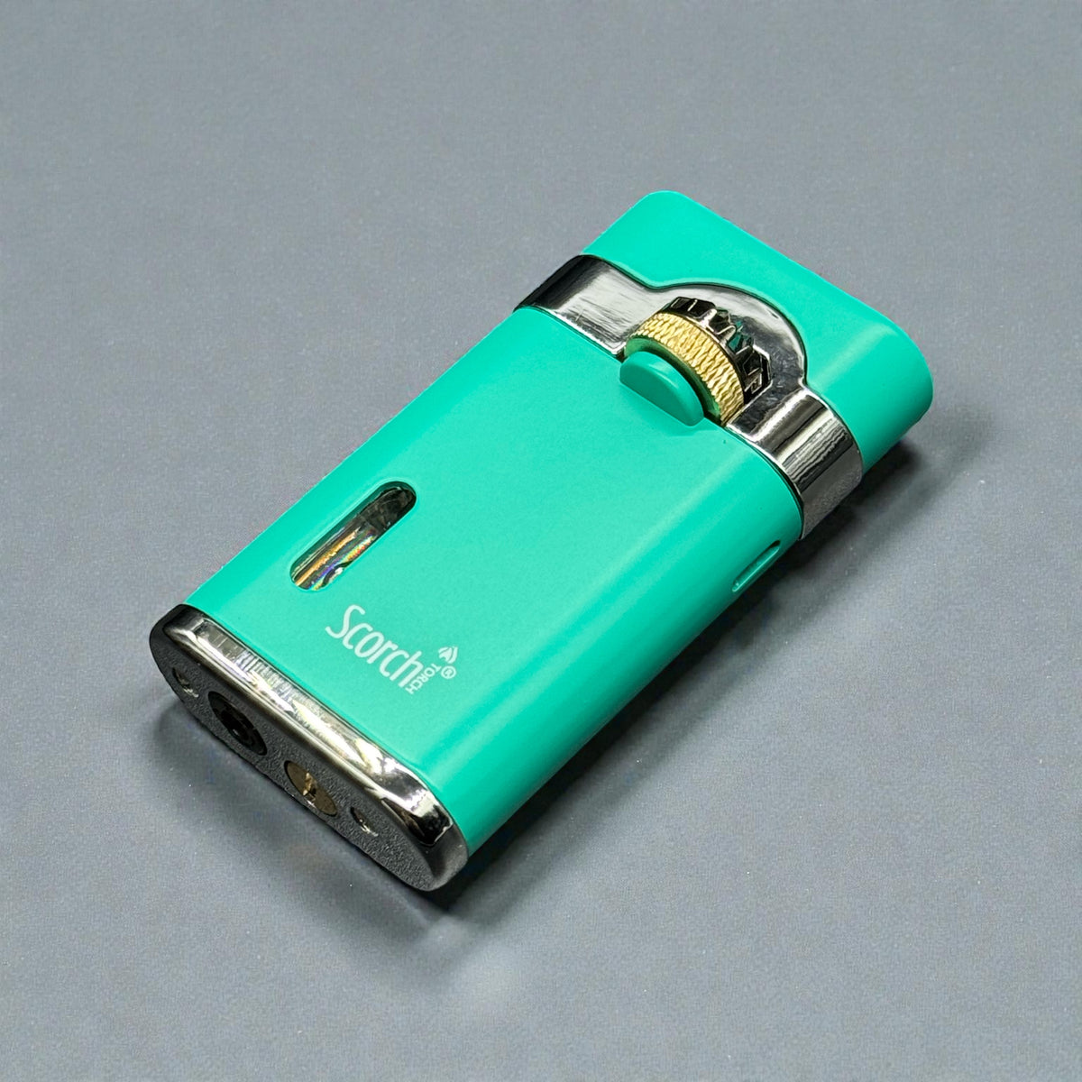 A turquoise green Scorch electronic vape pen with silver metallic accents and a gold-colored ignition button, resting on a neutral gray background.