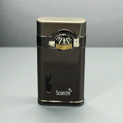 A metallic dark brown and silver Scorch portable lighter with a gold accent on the ignition button, standing upright on a gray surface.