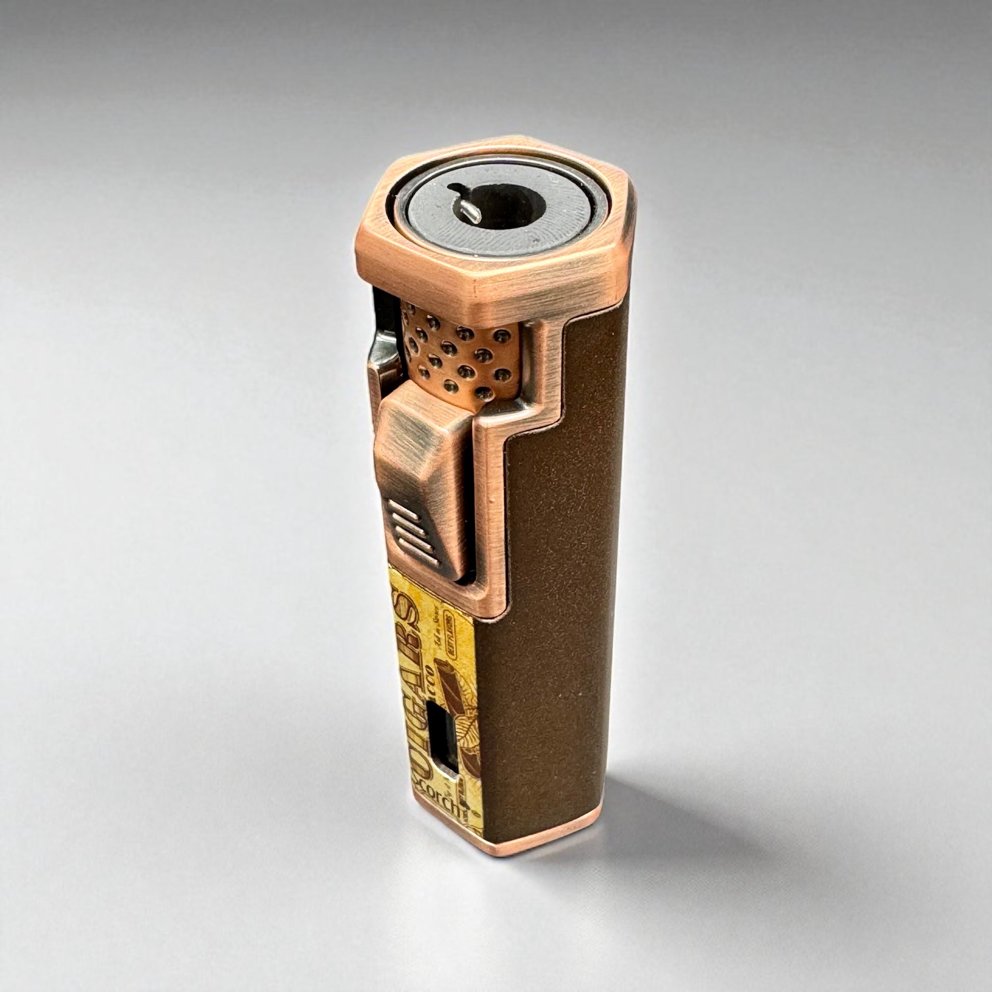 Bronze-colored lighter with intricate design on a gray background