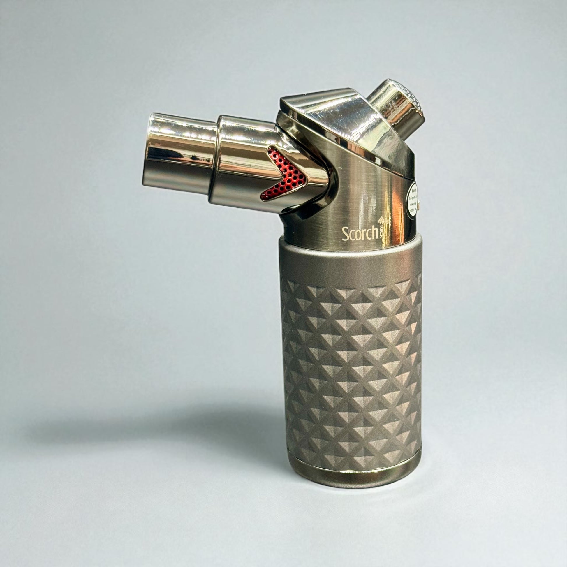 Metal butane lighter with textured design on a light gray background