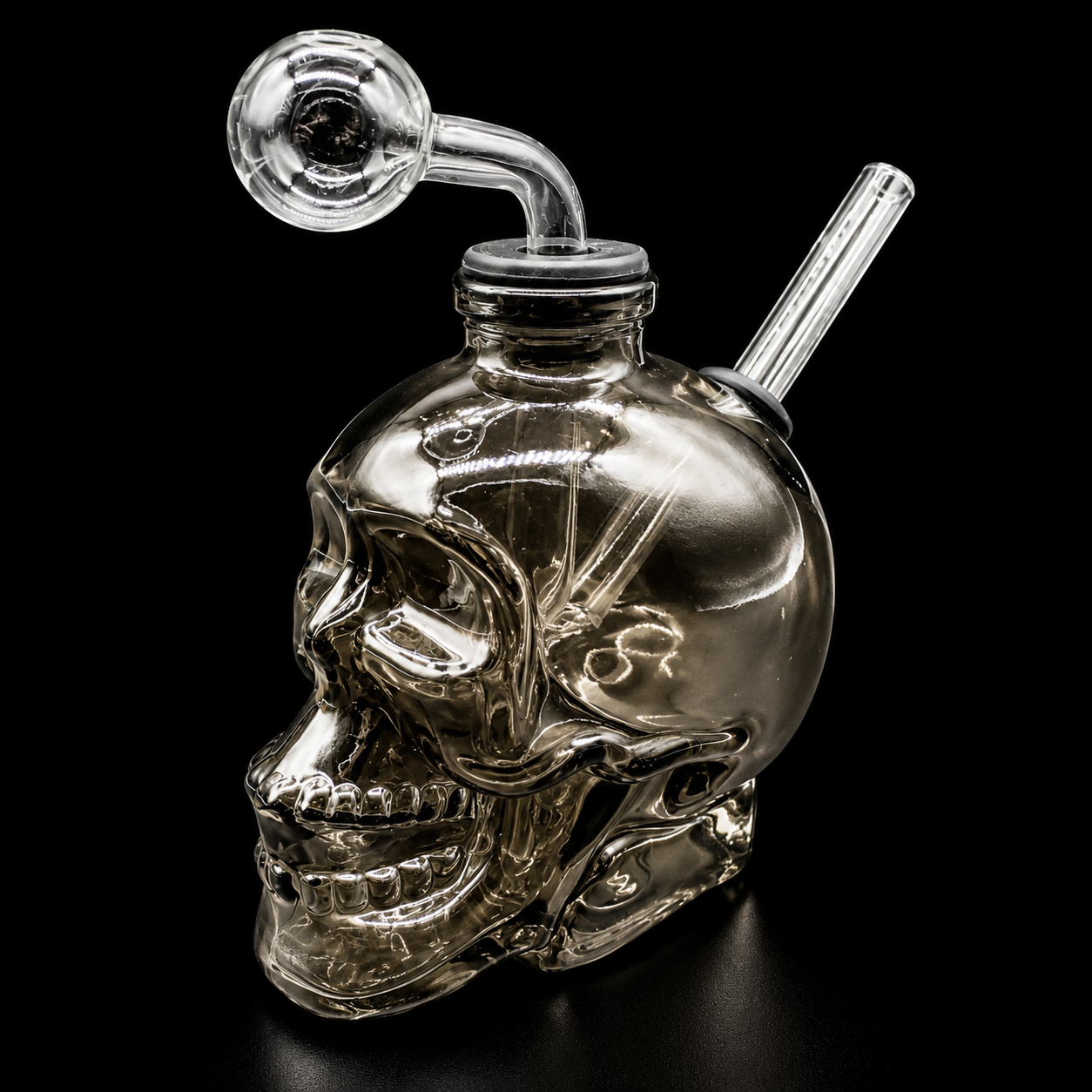 Clear glass skull-shaped smoking accessory with a hose on a black background