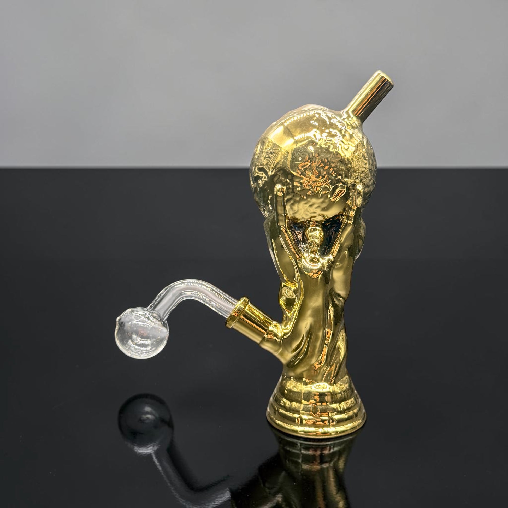 Gold-colored smoking accessory with a reflective surface on a gradient background
