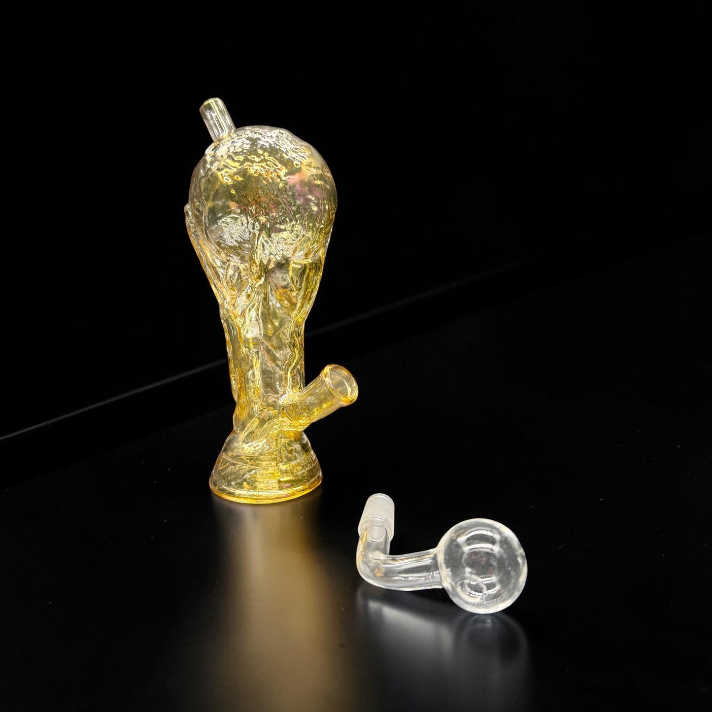 Glass smoking accessory with a yellowish tint on a black background