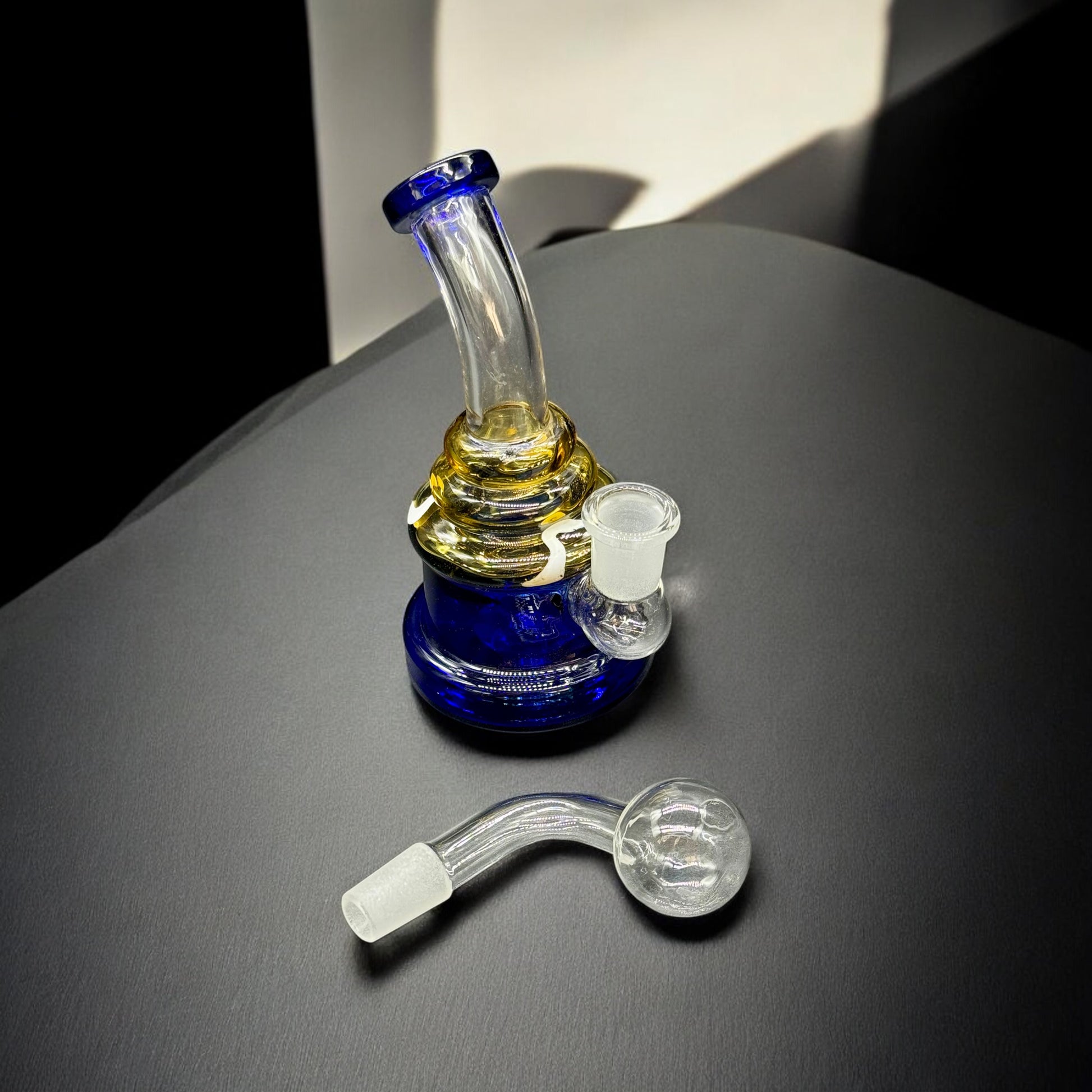 Side view of 5.5 inch blue and gold hand-blown mini glass rig with bent neck and separate glass bubble bowl