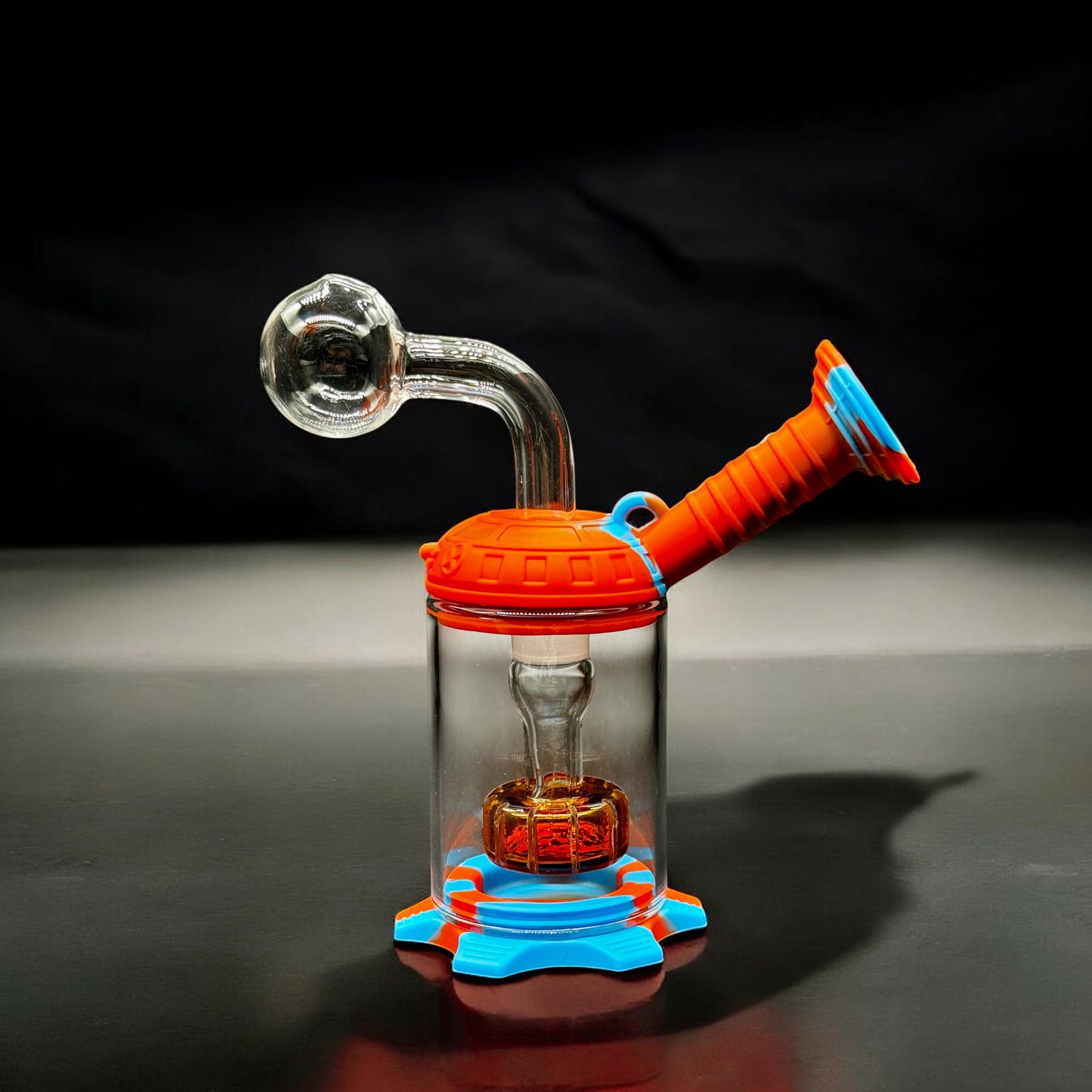 Mini water pipe featuring orange and blue silicone top and base with clear glass body