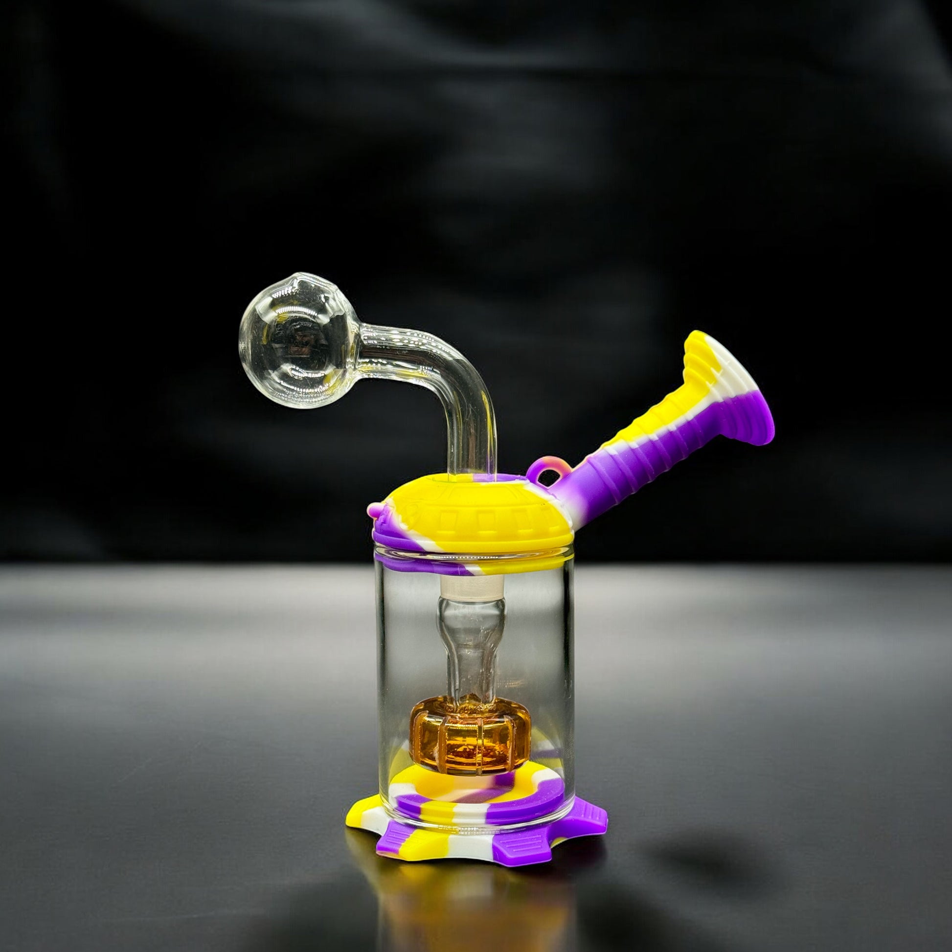 Mini dab rig with purple, yellow, and white silicone parts and clear glass chamber